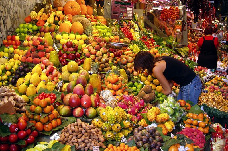 A heaped fresh-fruit stall piled with melons, mangoes, pineapples and tropical produce at the Mercat de la Boqueria off La Rambla, Barcelona