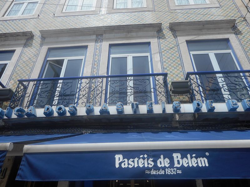 The blue awning and azulejo-tiled façade of the historic Pastéis de Belém custard-tart bakery in Lisbon