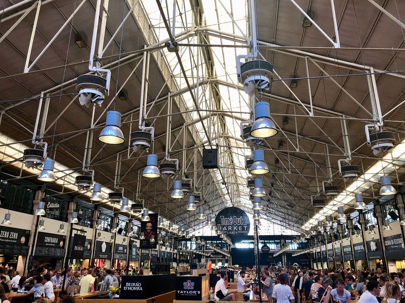The industrial roof and busy communal tables of the Time Out Market food hall at Cais do Sodré, Lisbon