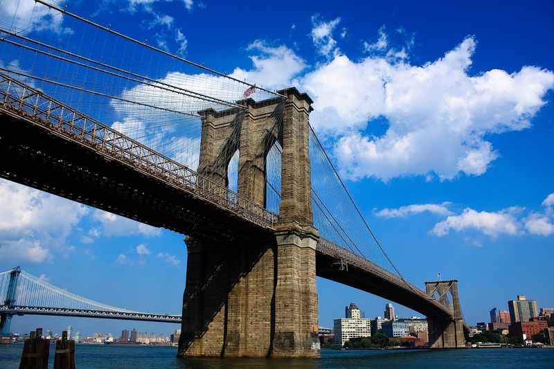 The gothic stone towers and steel cables of the Brooklyn Bridge against a blue sky, New York City