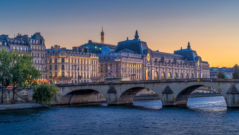 The Musée d'Orsay and its clock-topped former railway station seen across the Seine from the Pont Royal at dusk, Paris