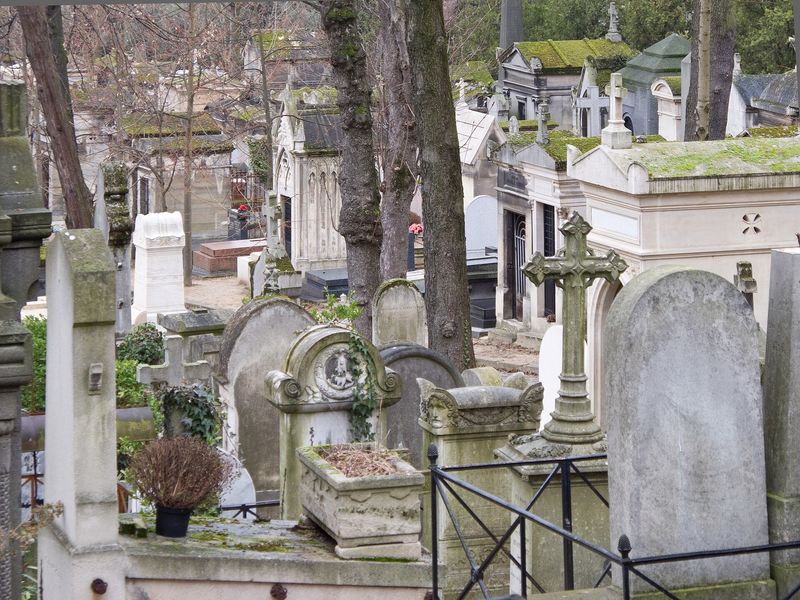 Moss-covered tombs, crosses and mausoleums among bare trees at Père Lachaise cemetery, Paris