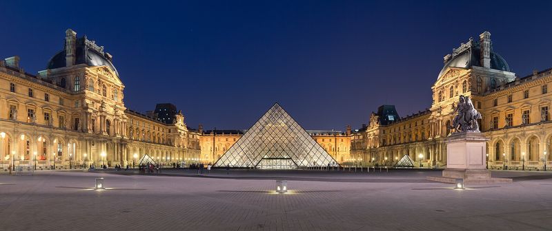 The glass Louvre Pyramid glowing at dusk in the Cour Napoléon of the Louvre Museum, Paris