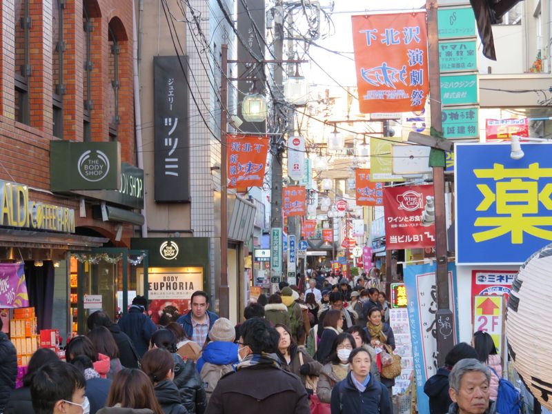 A crowded, car-free shopping lane in bohemian Shimokitazawa, Tokyo, hung with theatre-festival banners and shop signs